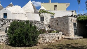 A traditional white building with a stone wall and a small garden area.