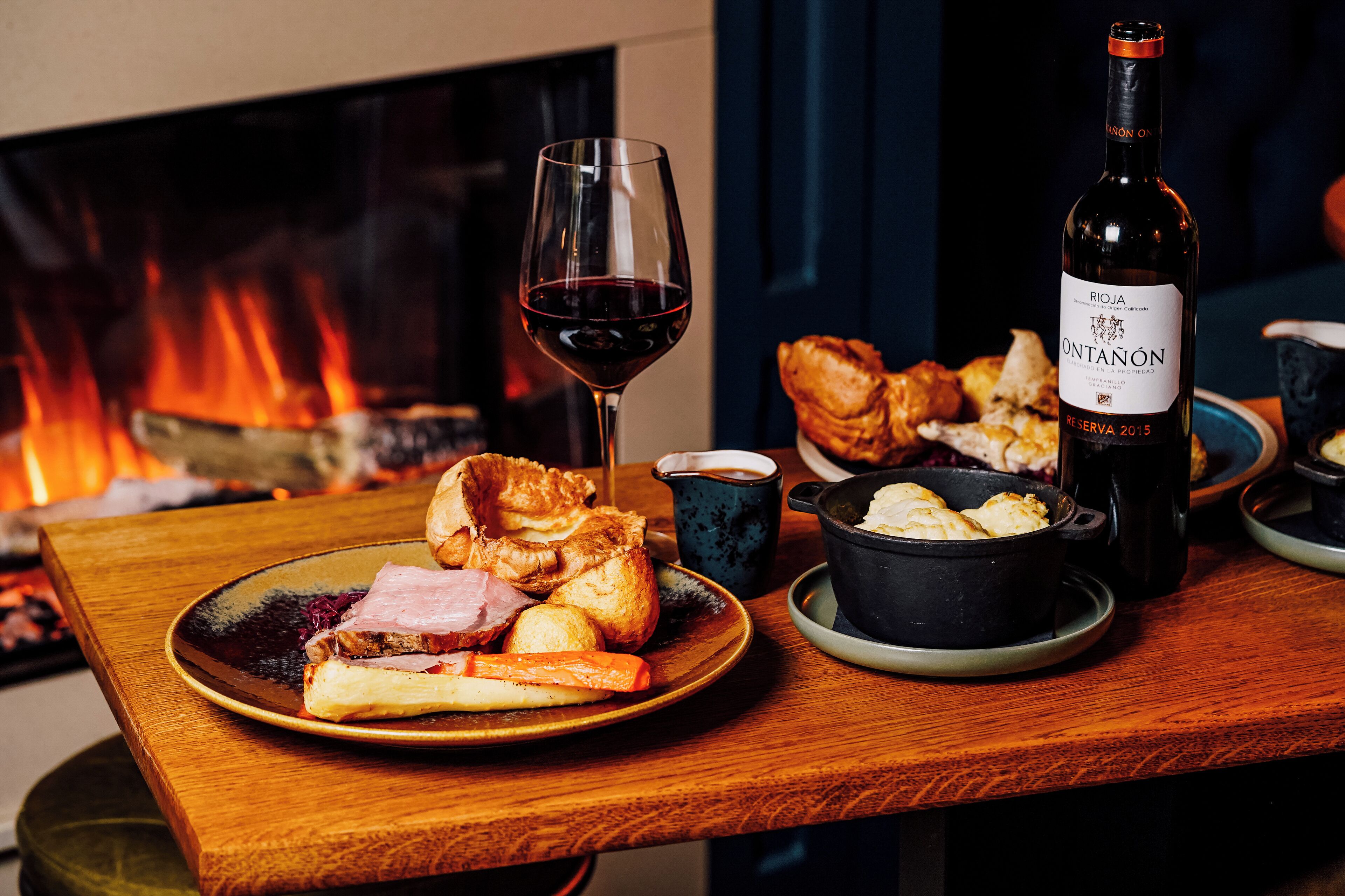 Una mesa de comedor con platos de comida, una copa de vino y una botella.
