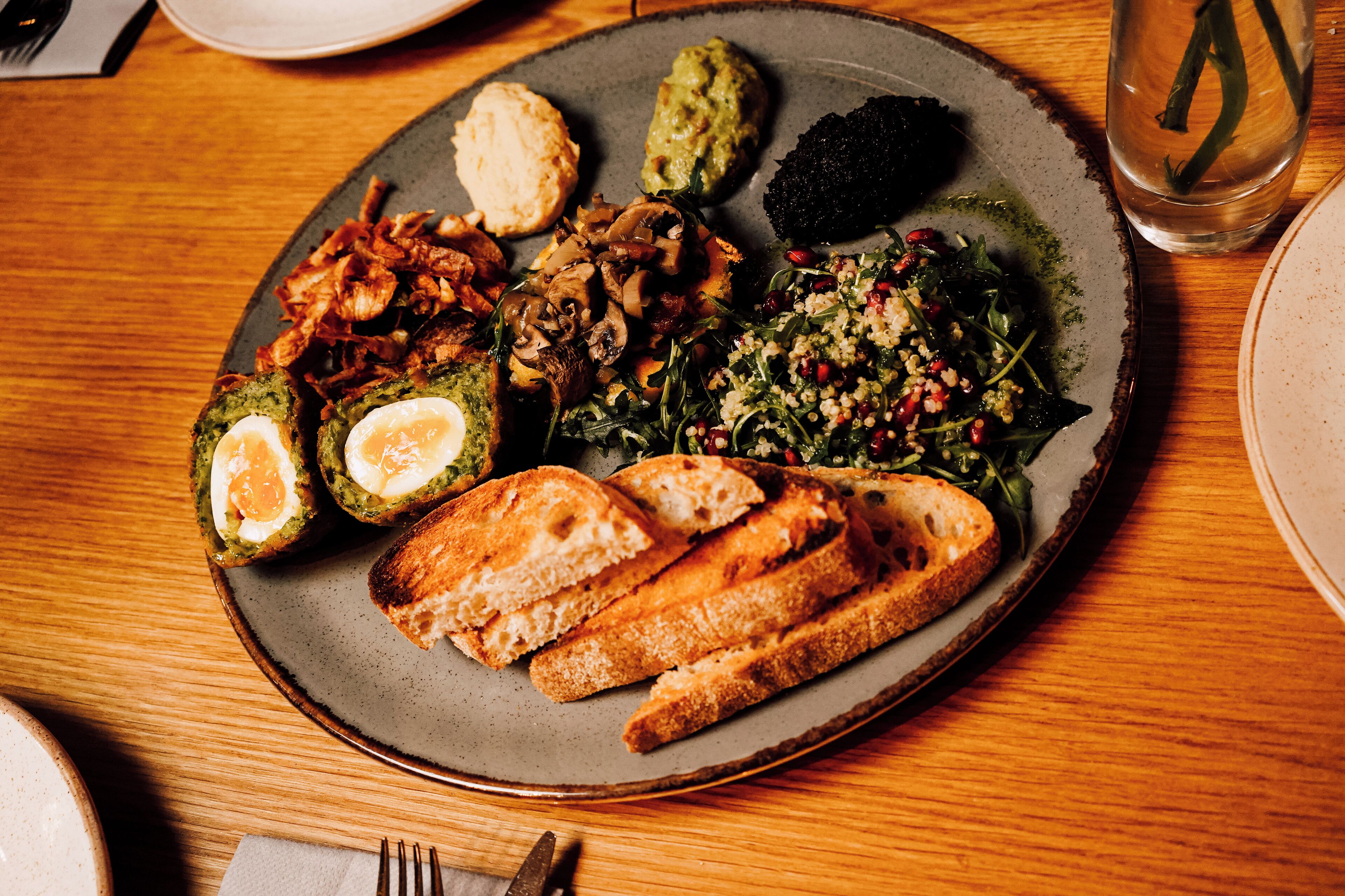 A plate of food with various items including bread, mushrooms, and greens.