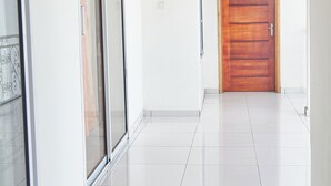 Een hal met een houten deur, een schuifdeur van glas en een plafondlamp.