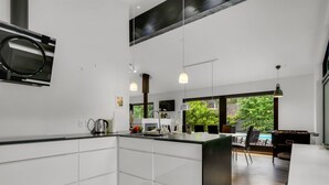 Una cocina moderna con armarios blancos, una isla central e iluminación colgante.