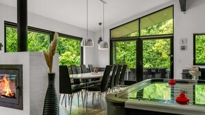 Un comedor moderno con una mesa de vidrio, sillas negras y una chimenea.