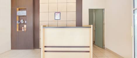 A reception area with a wooden reception desk, a wall-mounted bulletin board, and a green door.