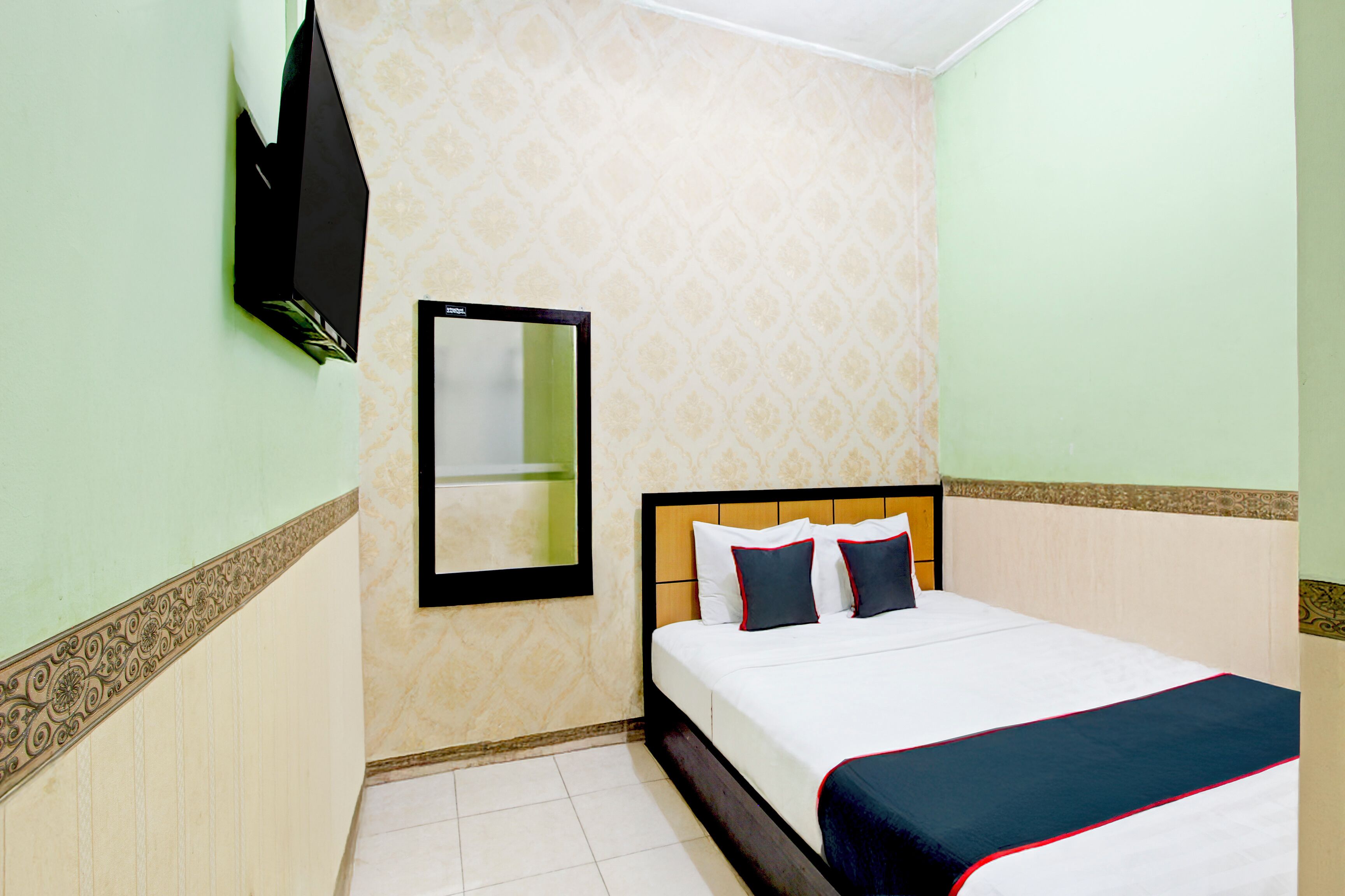 Une chambre d’hôtel avec un lit, un miroir et un papier peint à motifs.