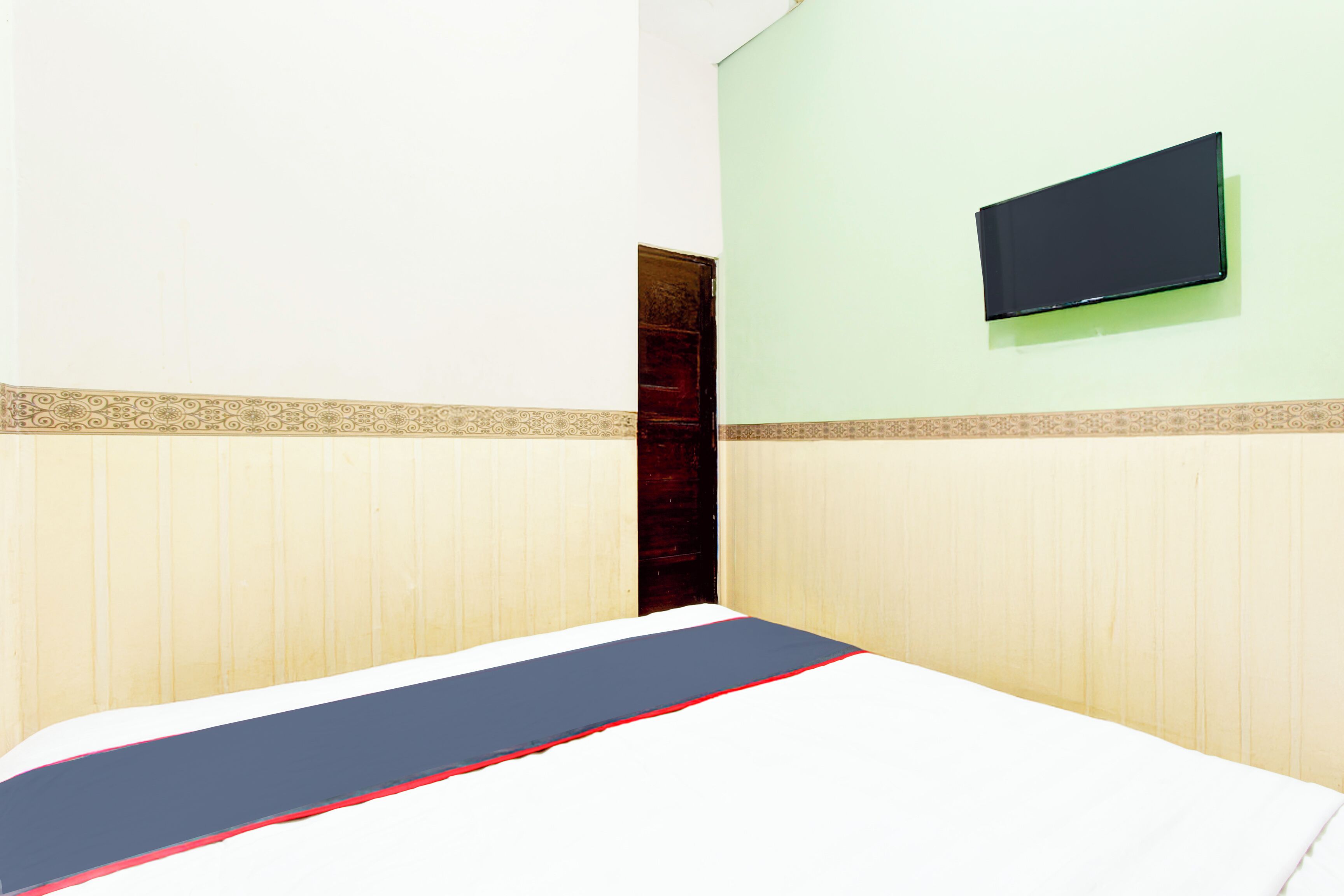 A room with a bed, a television mounted on the wall, and a door.