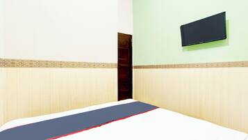 A room with a bed, a television mounted on the wall, and a door.