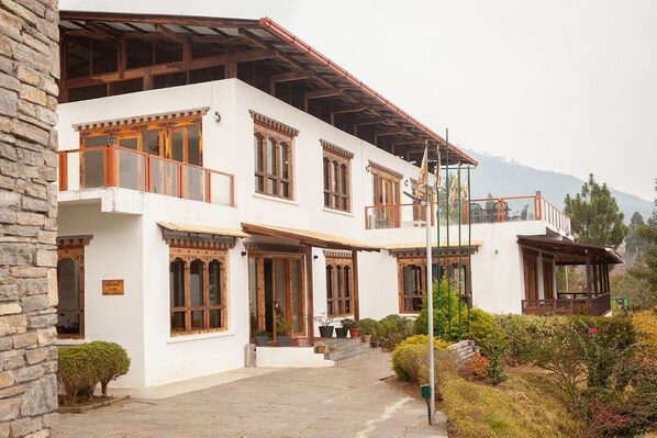 A two-story building with a restaurant sign, wooden balconies, and a garden area.