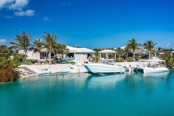 Un port de plaisance avec des bateaux amarrés, une piscine et un bâtiment à la façade blanche et aux colonnes.