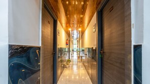 Un pasillo moderno con piso de mármol pulido, puertas de vidrio y techo de madera.