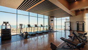 Un gimnasio moderno con amplias ventanas, equipamiento de ejercicio y suelo de madera.