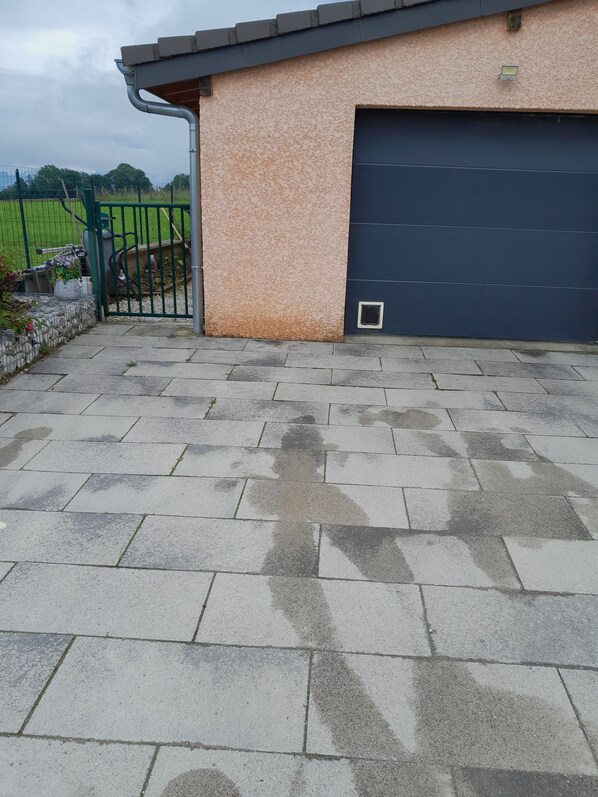 A paved driveway leading to a garage with a textured wall and a metal gate.