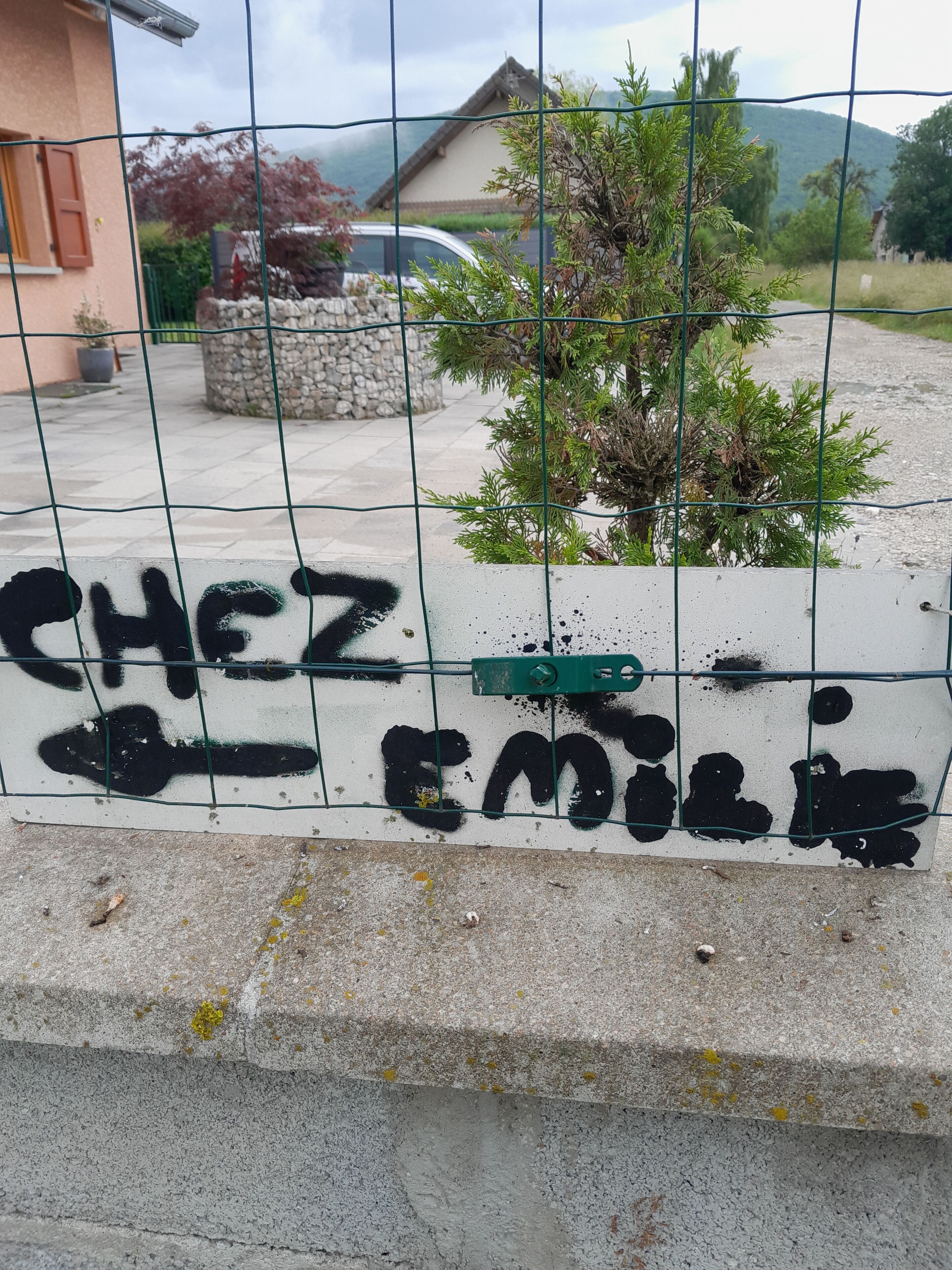 A concrete wall with graffiti and a green street sign.