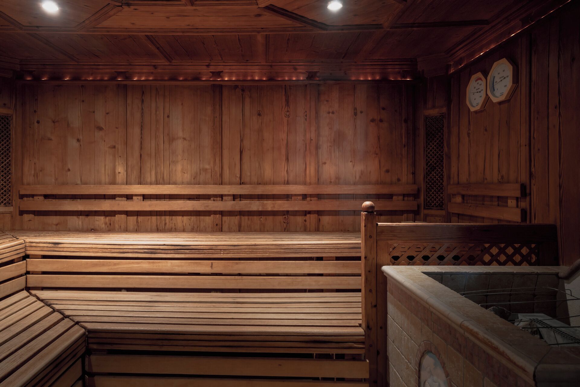 A sauna with wooden benches and a stone hot tub.