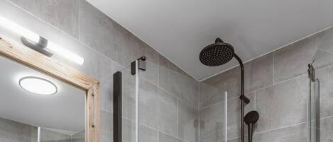 A modern bathroom with a glass-enclosed shower, a white sink, and a wooden vanity.