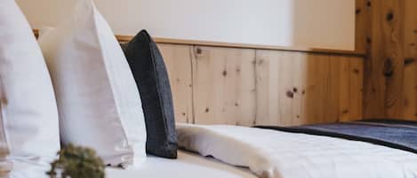 A bed with white and black pillows, a wooden headboard, and a wooden wall.