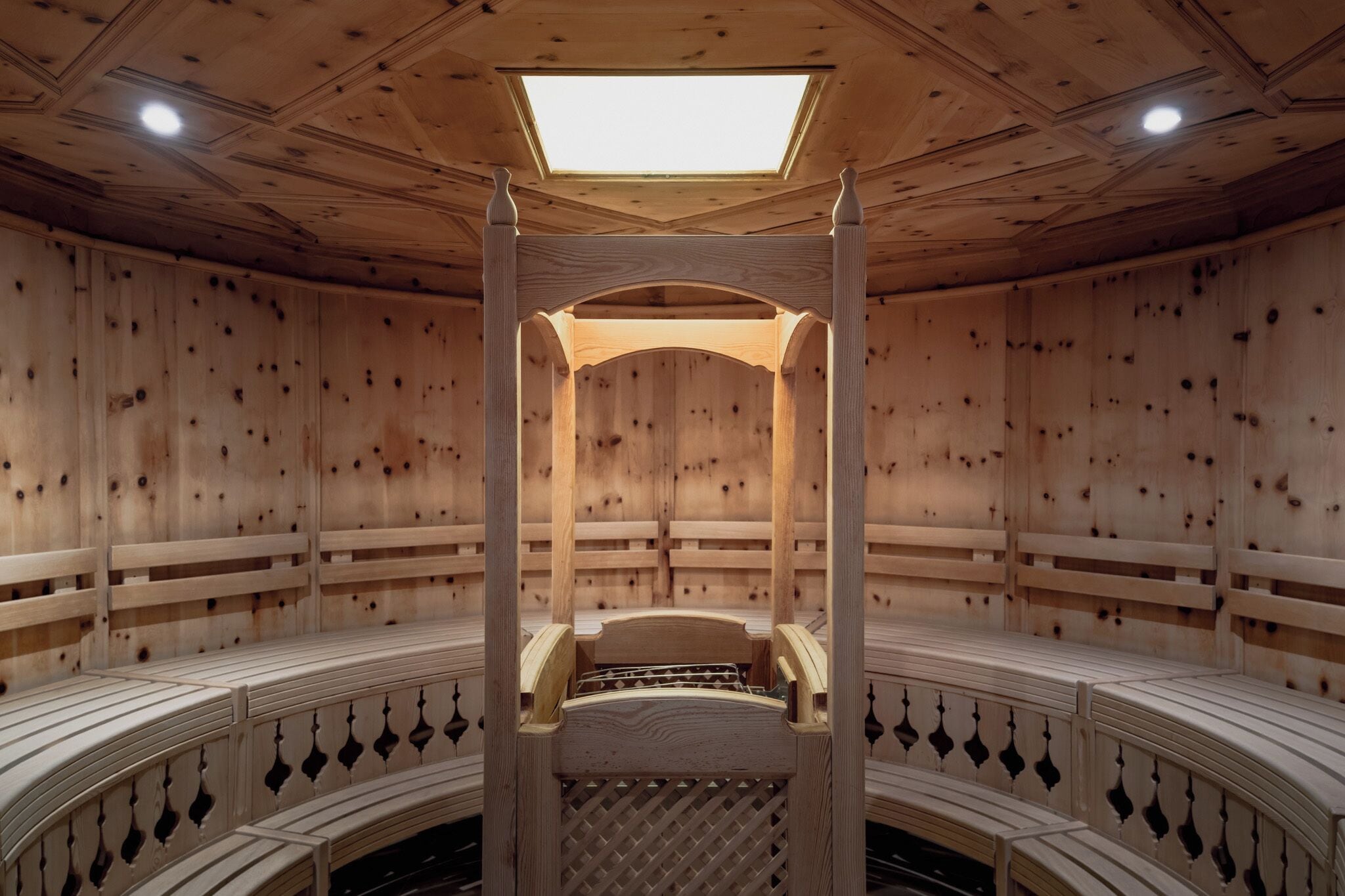 A sauna with a wooden interior, a central bench, and a skylight.
