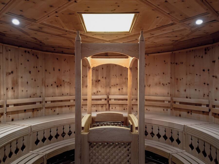 A sauna with a wooden interior, a central bench, and a skylight.