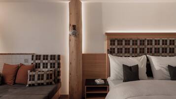 Ein Schlafzimmer mit einem Bett, einem Nachttisch, einer Holzsäule und einem Sofa.