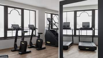A gym with treadmills, elliptical machines, and a mirror reflecting the space.