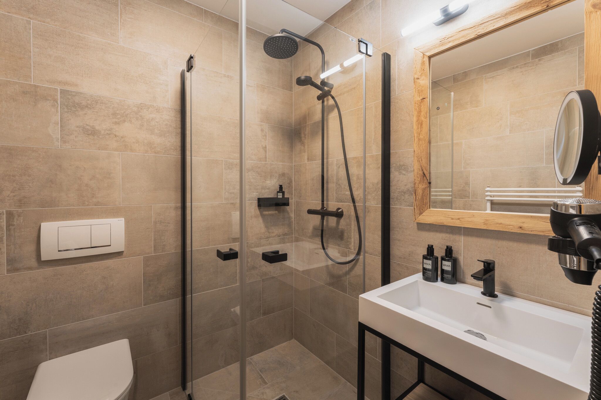 Un bagno moderno con doccia vetrata, lavabo bianco e specchio.