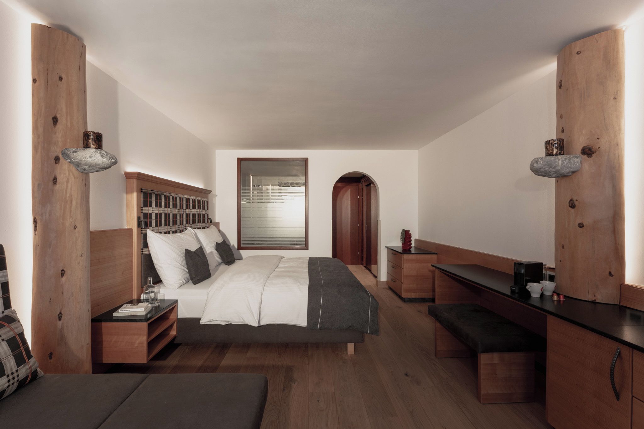 Ein modernes Schlafzimmer mit einem großen Bett, Nachttischen, einer Bank und einem Schreibtisch.