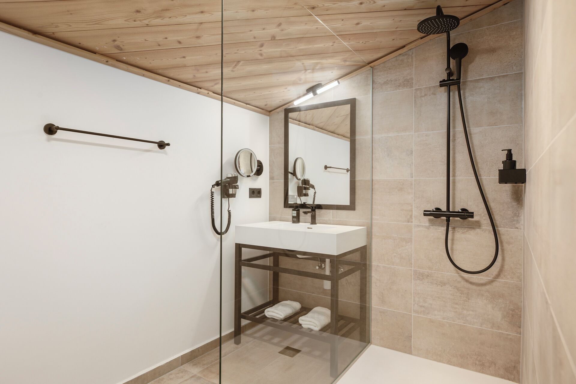 Een moderne badkamer met een douchecabine van glas, een witte wastafel en een spiegel.