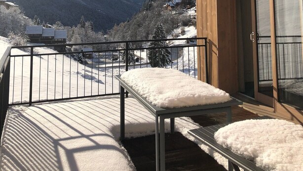 Un bâtiment en bois doté d’un balcon donnant sur un paysage montagneux enneigé.