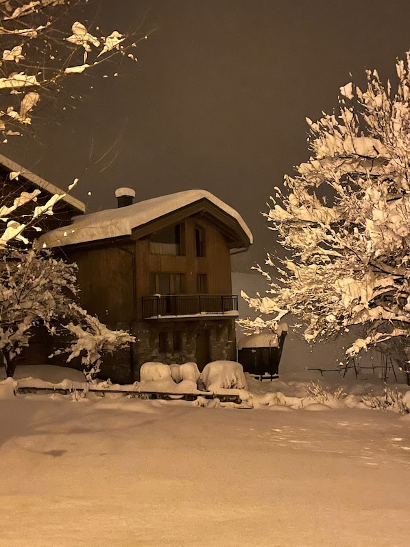 Una casa cubierta de nieve con balcón, rodeada de árboles.