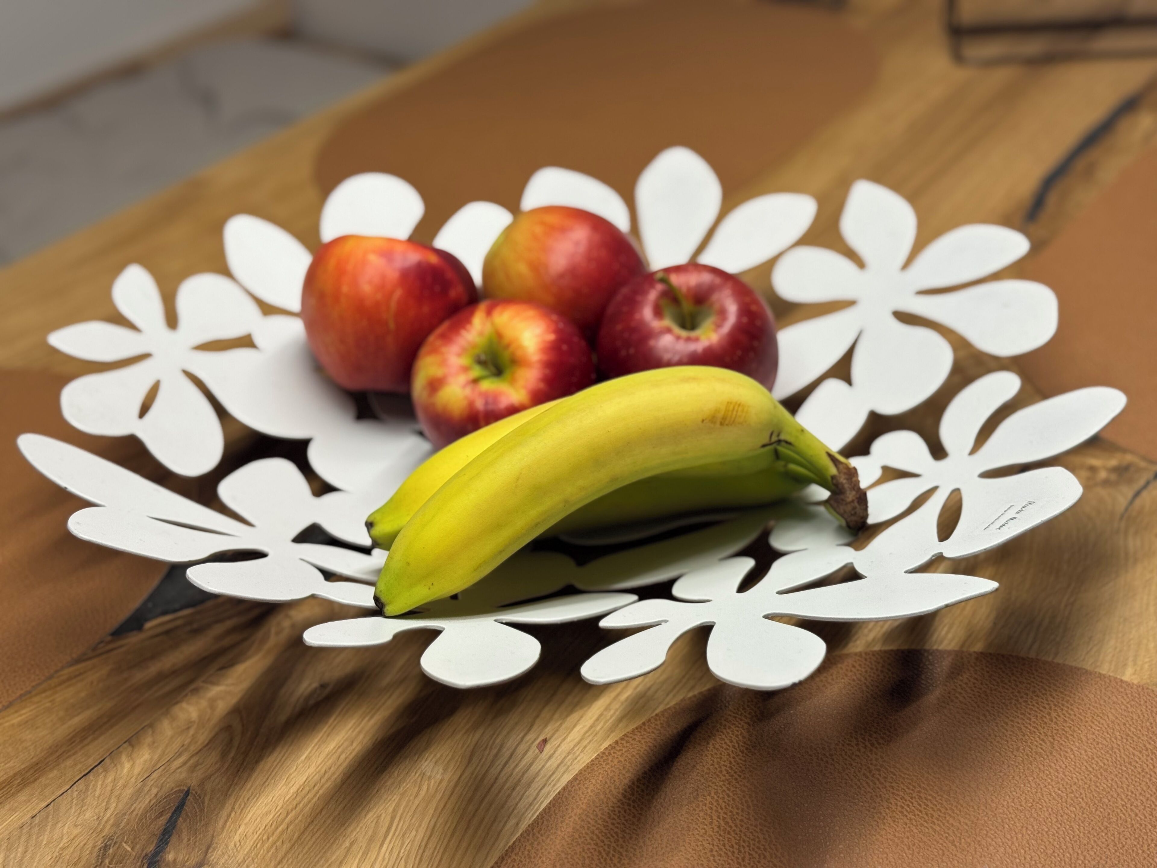 Une table en bois sur laquelle est posée une nappe décorative blanche ornée d’un motif floral.