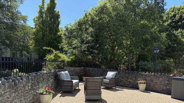 Un espace extérieur aménagé en terrasse, avec des meubles en osier et des murs en pierre.
