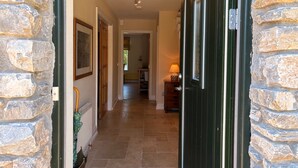 Un couloir aux murs de pierre, une porte et une lampe.