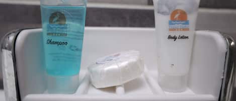 A bathroom shelf with a shampoo bottle, a body lotion tube, and a bar of soap.