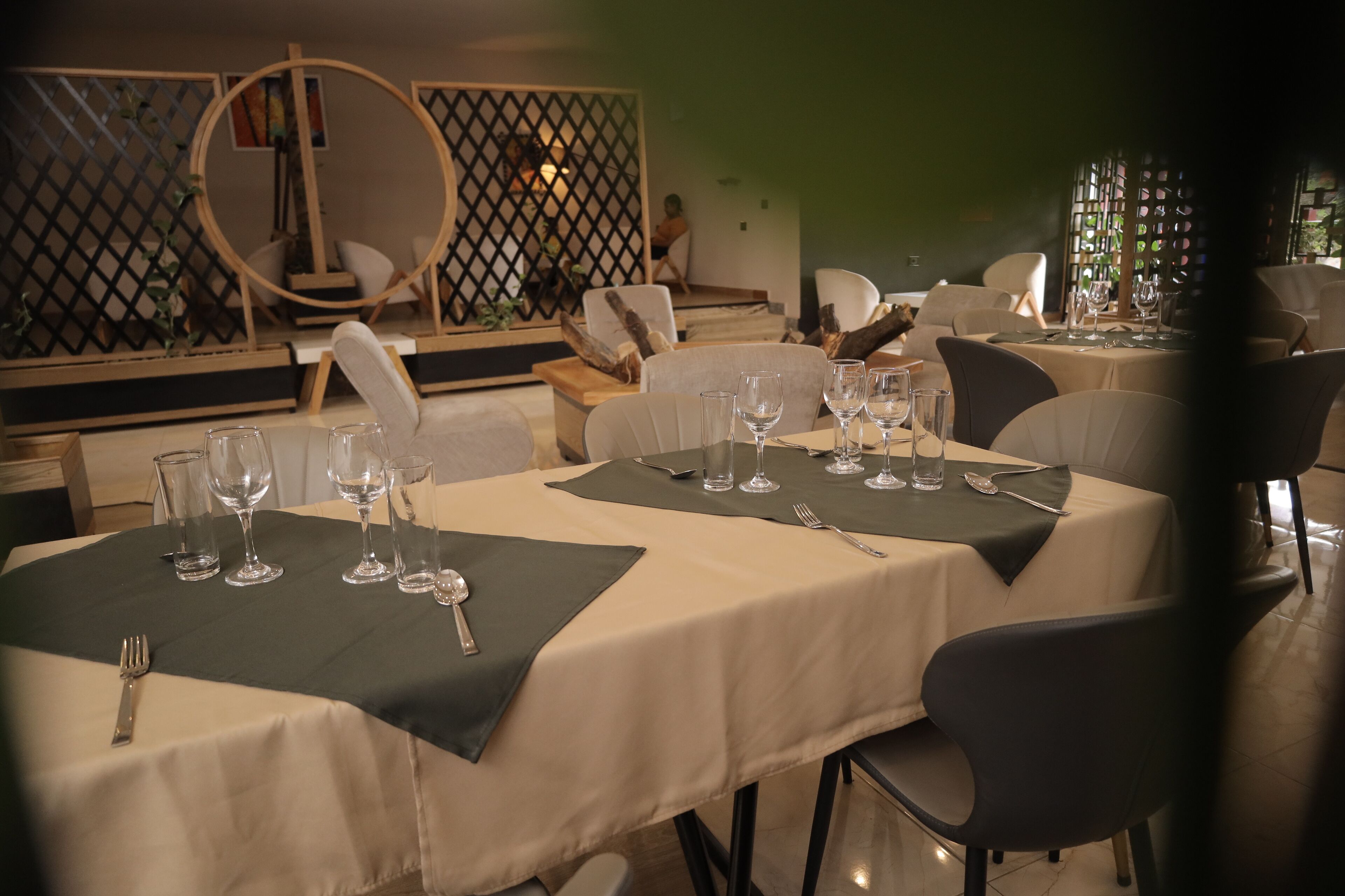 Un restaurant doté de tables rondes aménagées pour les repas, avec une palette de couleurs neutres et un design moderne.