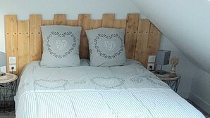 A bed with a wooden headboard, two pillows with heart designs, and a striped bedspread.