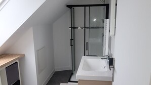 A modern bathroom with a skylight, a shower, and a vanity.