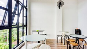 A room with large windows, multiple tables, and chairs. - Capital O 94254 Dental Inn (Banda Aceh)