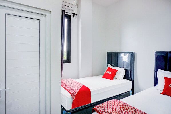 Habitación de hotel con dos camas, cada una con una colcha de cuadros rojos y blancos, cabecero negro y almohada con el logotipo "OYO".