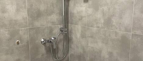 A modern shower with a handheld showerhead, a wall-mounted control panel, and a white bathtub.