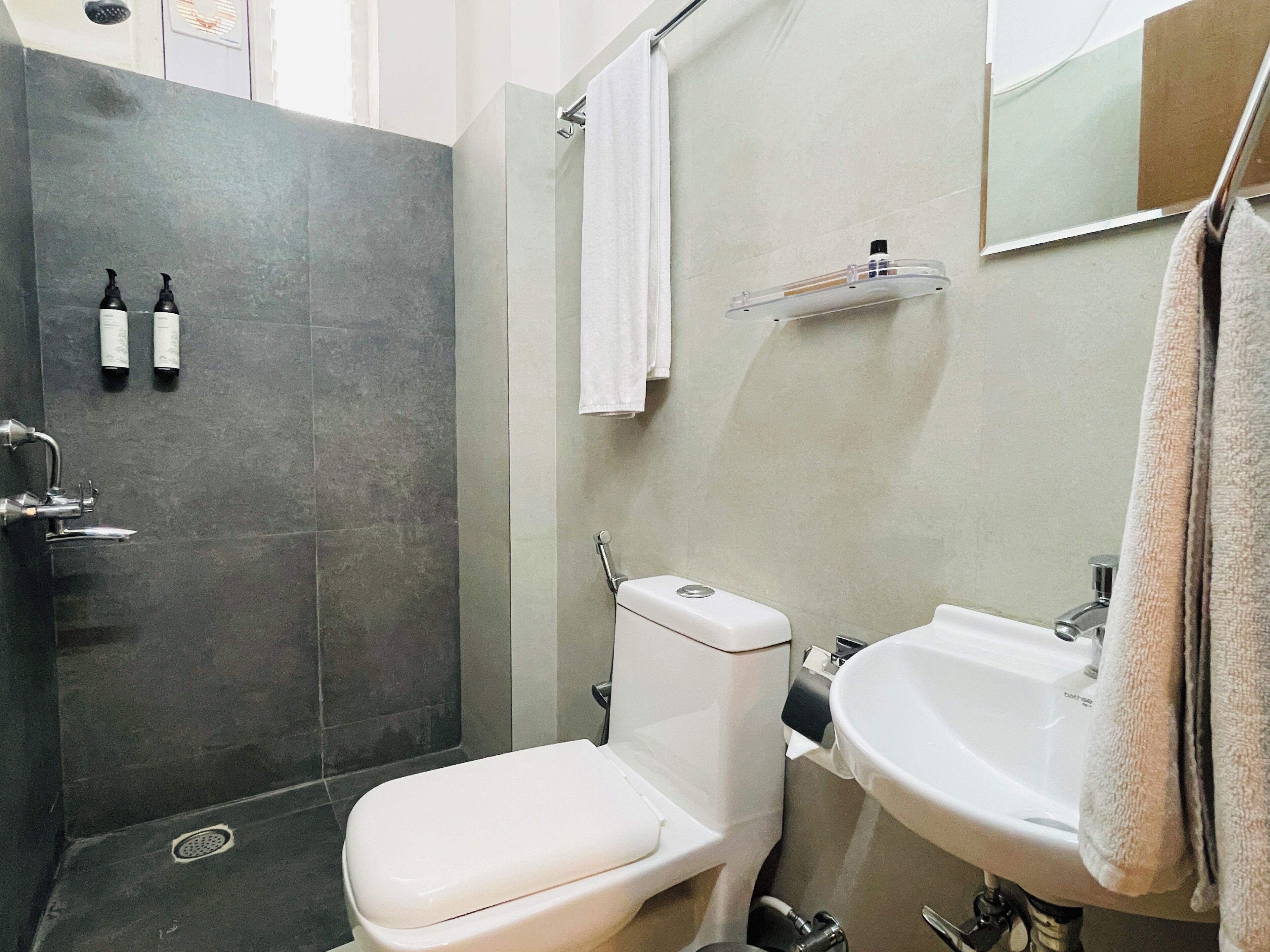 A bathroom with a shower, toilet, sink, and towel rack.