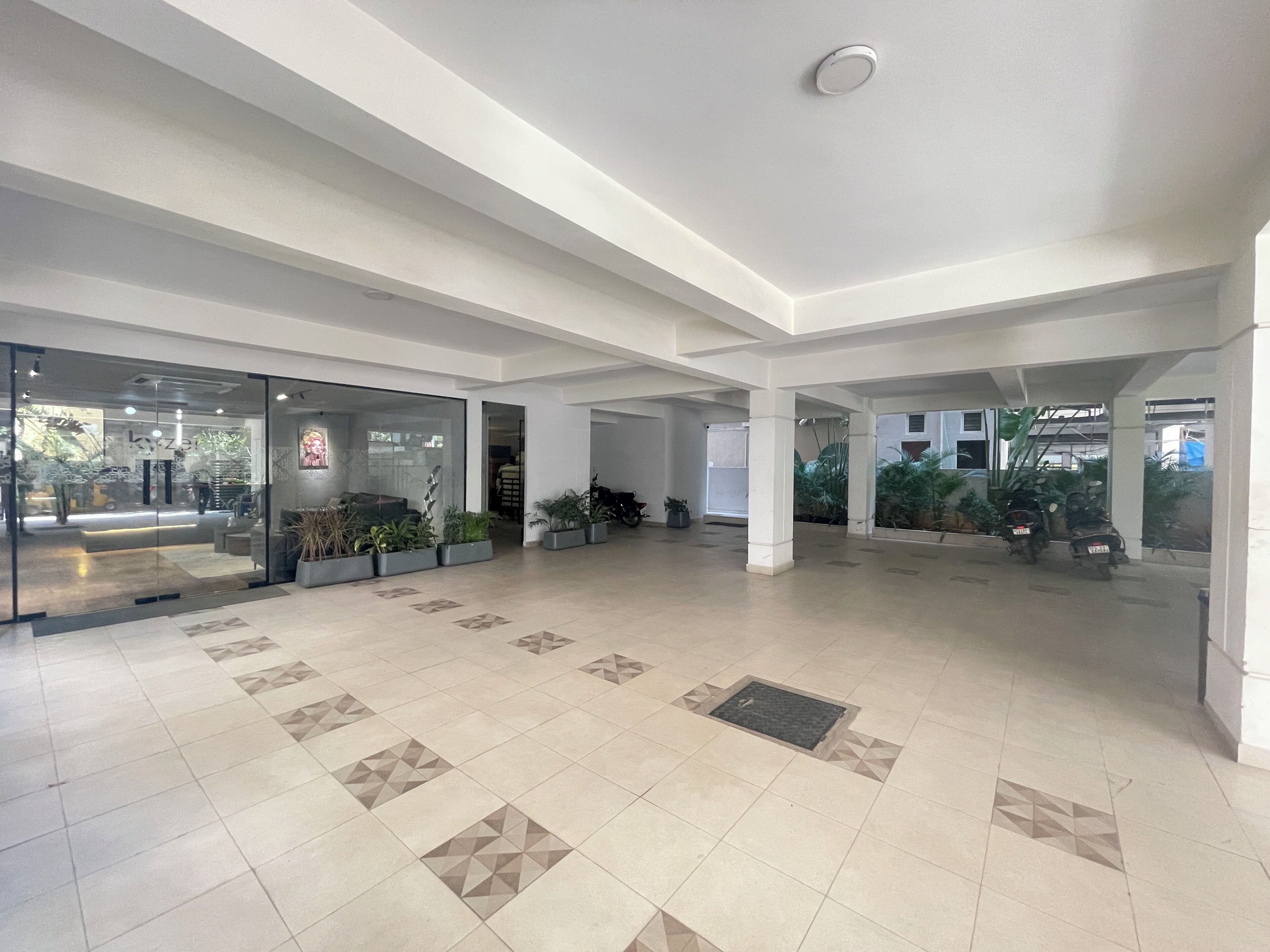 An indoor space with a tiled floor, glass doors, and potted plants.