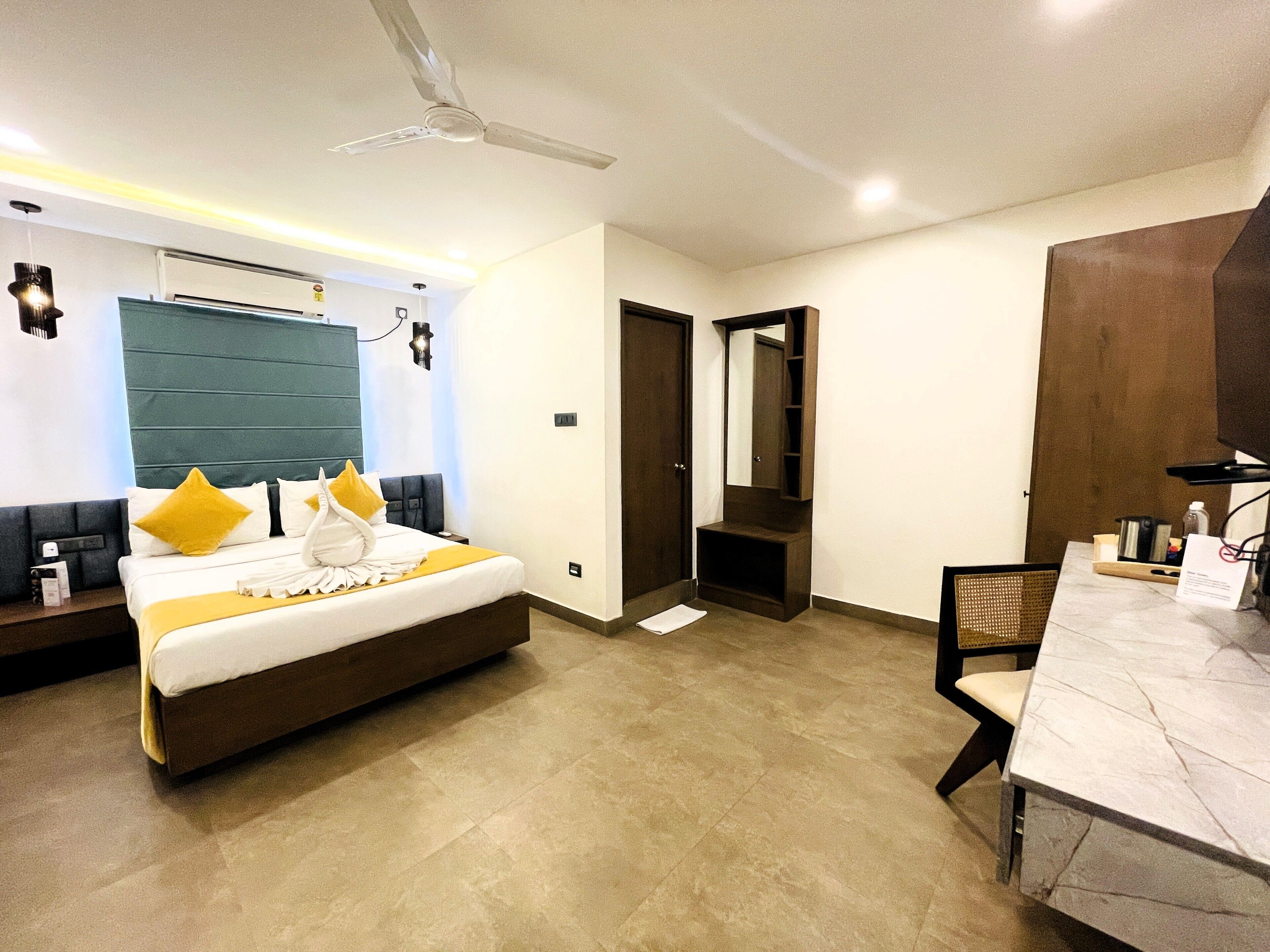 A hotel room with a bed, bedside table, desk, chair, and a ceiling fan.