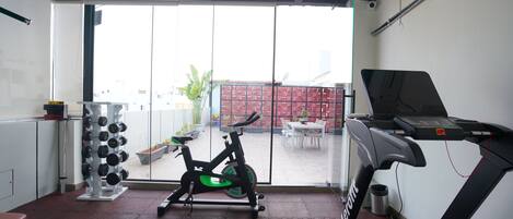 A gym with a treadmill, stationary bike, and weight rack.