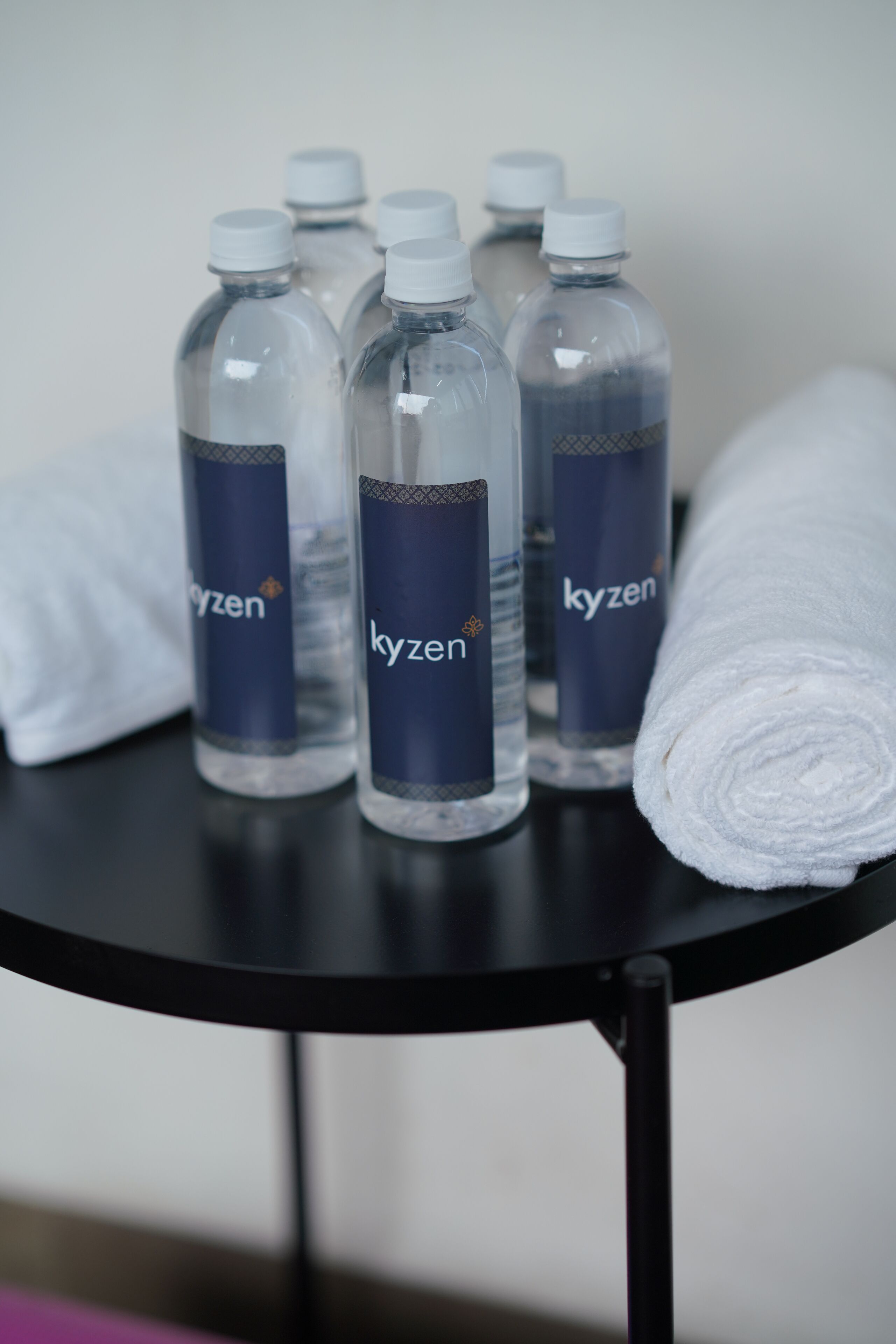 Une table avec six bouteilles d’eau Kyzen et une serviette blanche roulée.