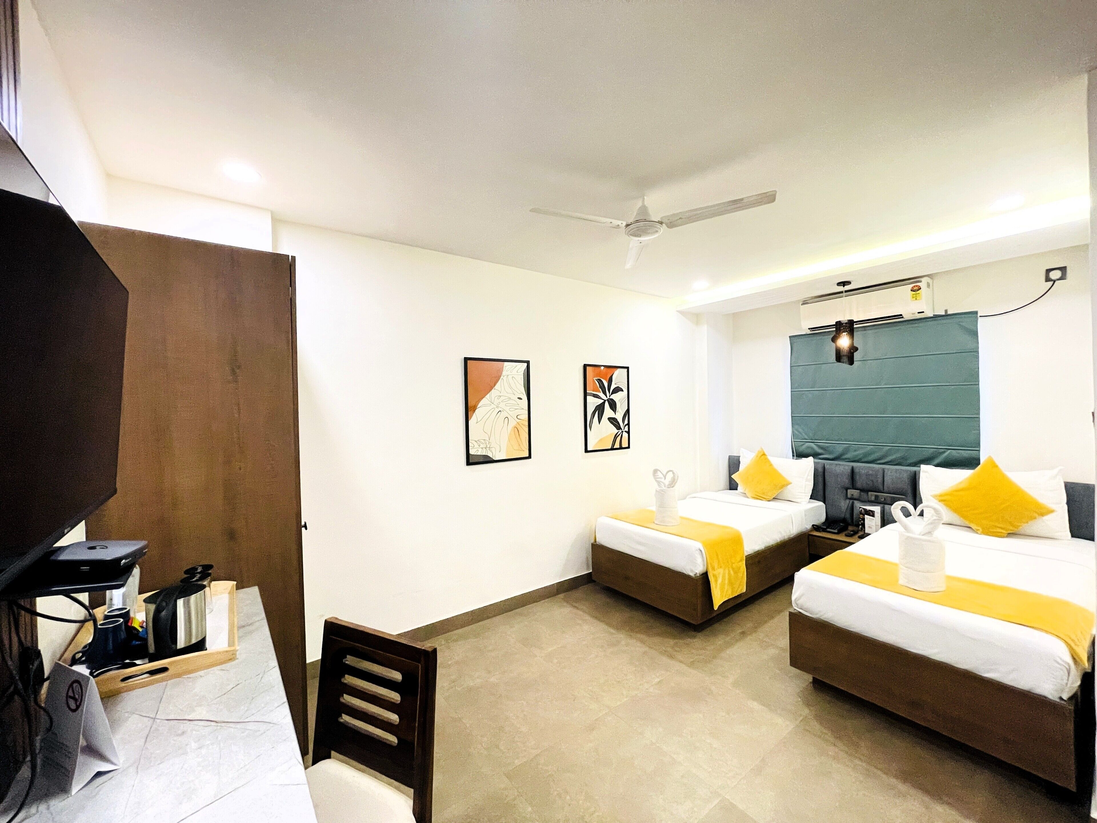 A hotel room with two beds, a desk, a chair, and artwork on the walls.