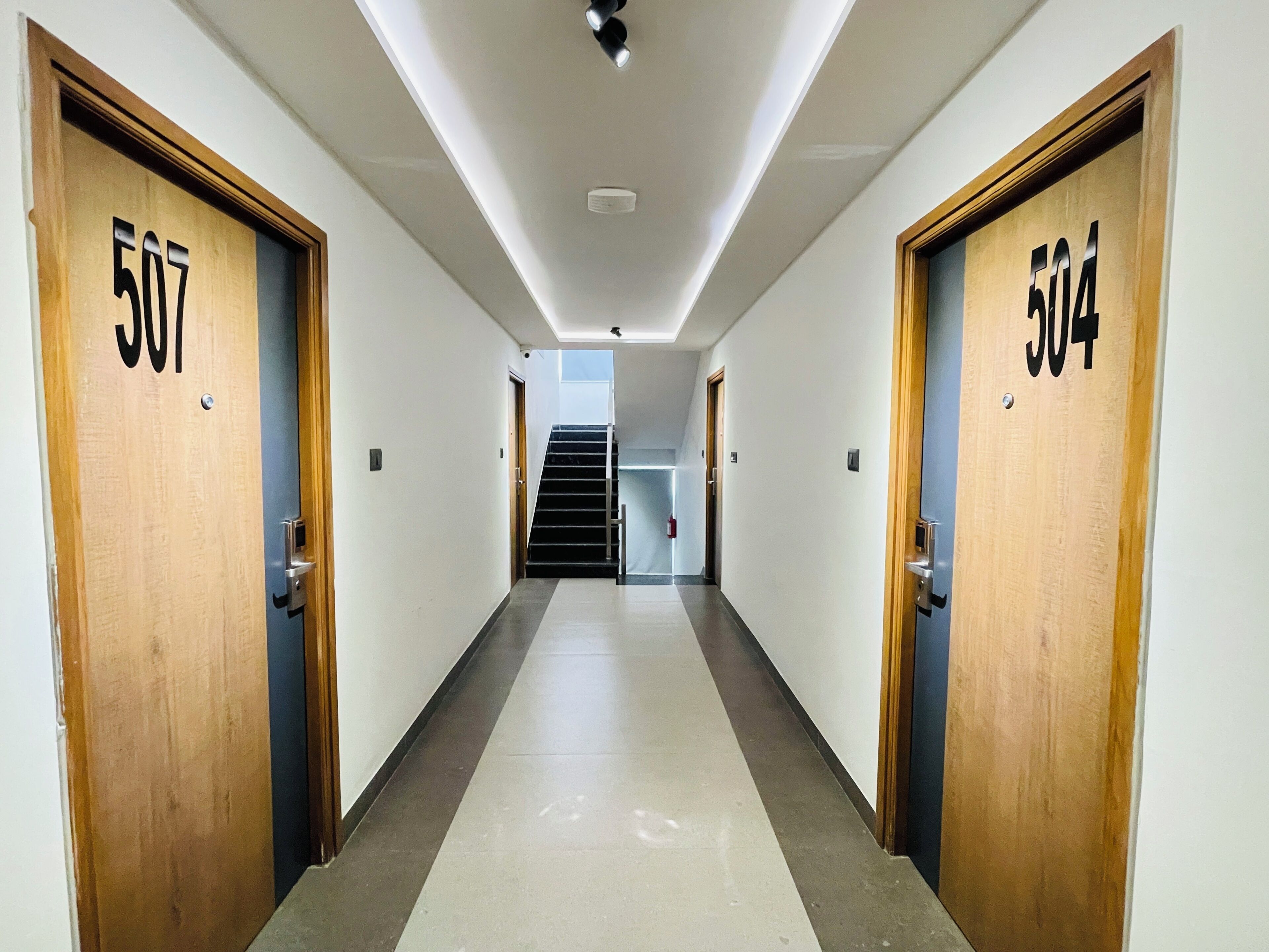 Un couloir avec les portes numérotées 507 et 504, qui mène à un escalier.