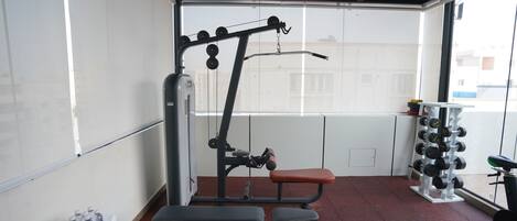 Une salle de sport équipée de matériel d’exercice, d’un banc et d’un porte-haltères.