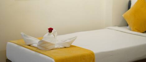 A hotel room with a bed, a yellow bedspread, a white pillow, and a wall art piece.