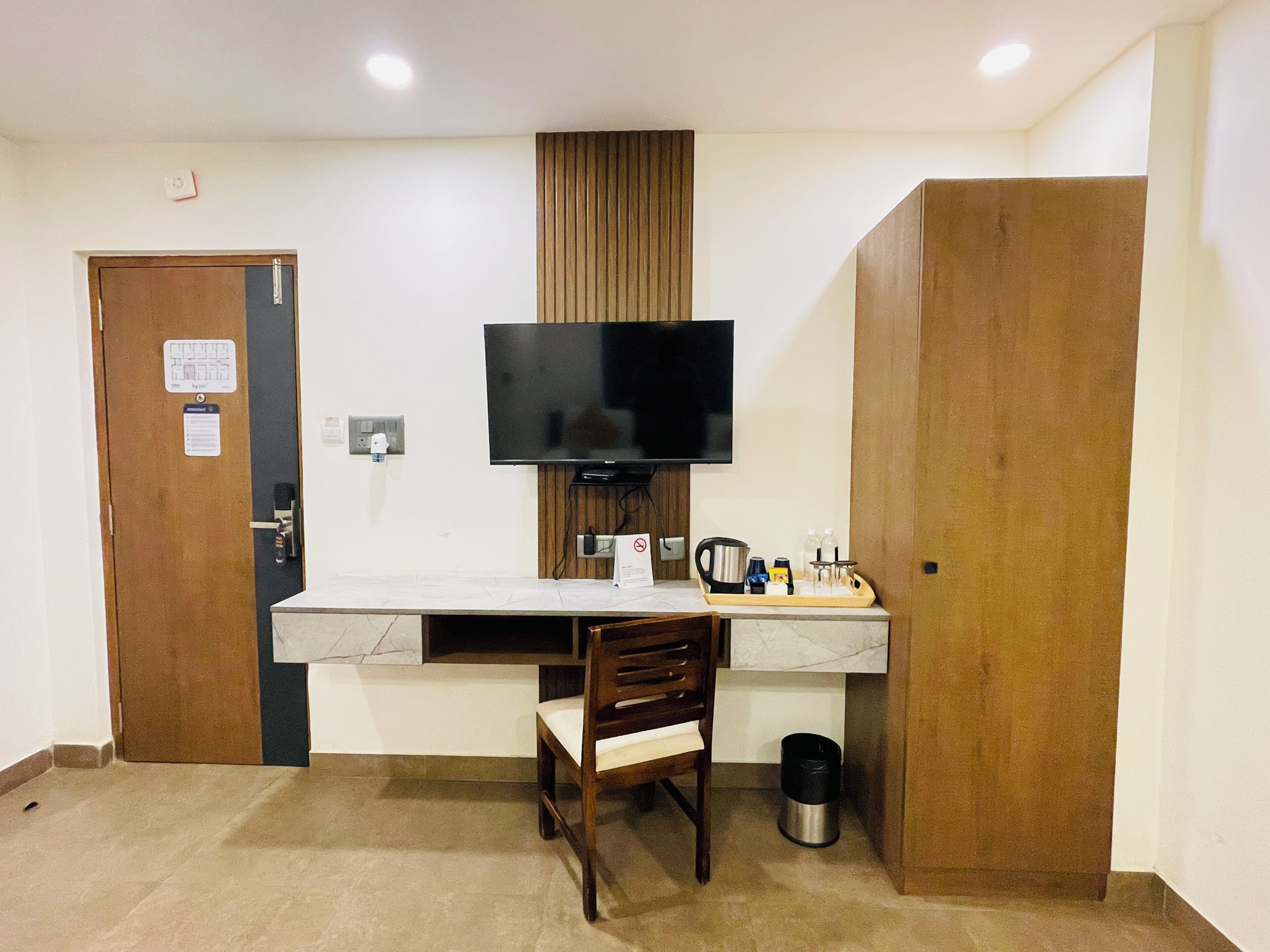 A small room with a desk, chair, television, and a wooden wardrobe.
