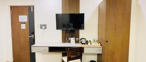 Una stanza piccola con una scrivania, una sedia, una televisione e un armadio in legno.