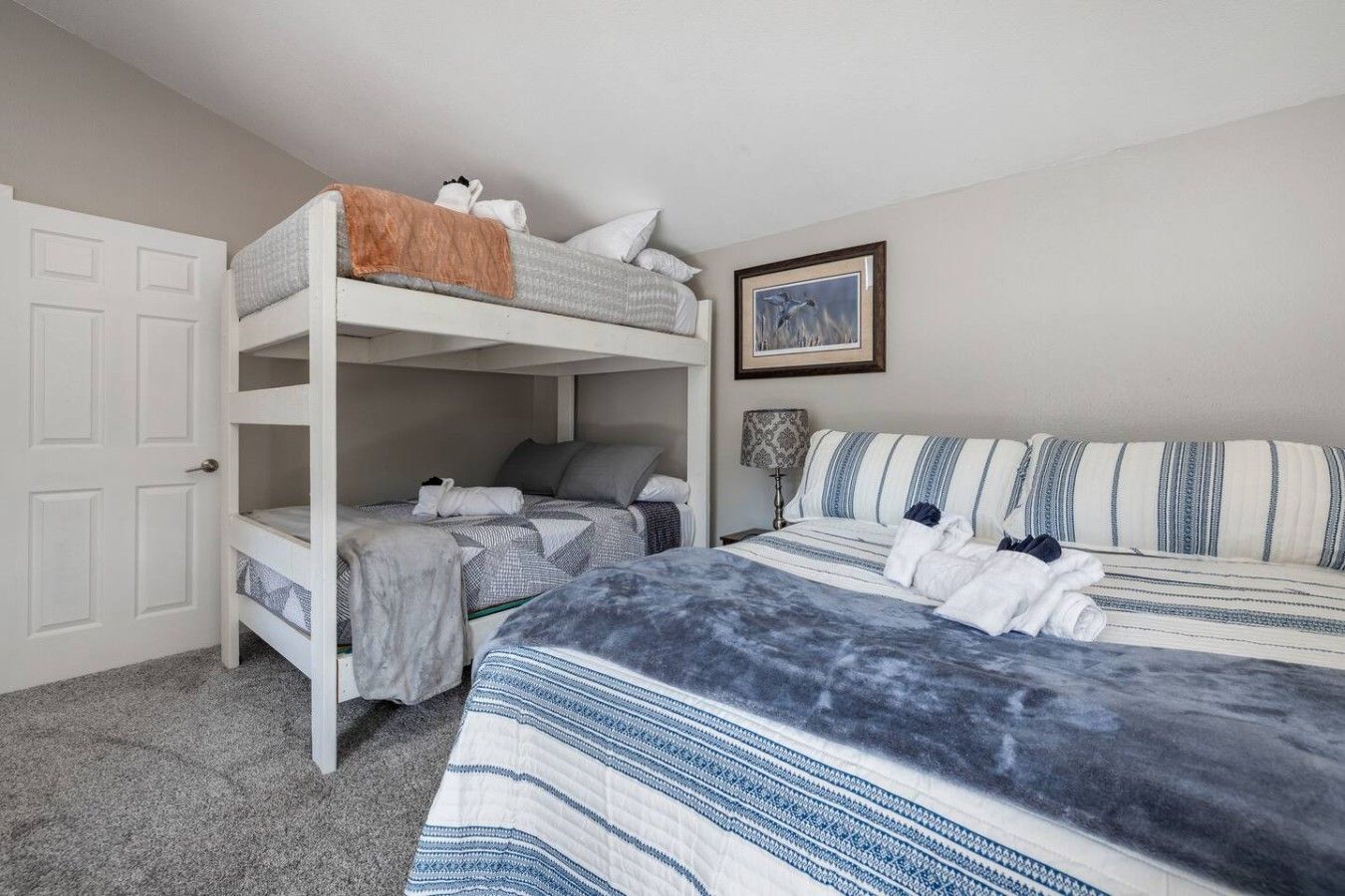 Ein Schlafzimmer mit Etagenbetten, einem Einzelbett und einem gerahmten Bild an der Wand.